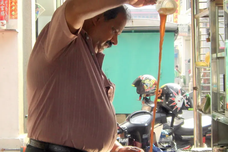 Teh tarik being poured, showing its characteristic foam