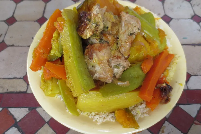 A plate of steamed couscous with vegetables and meat
