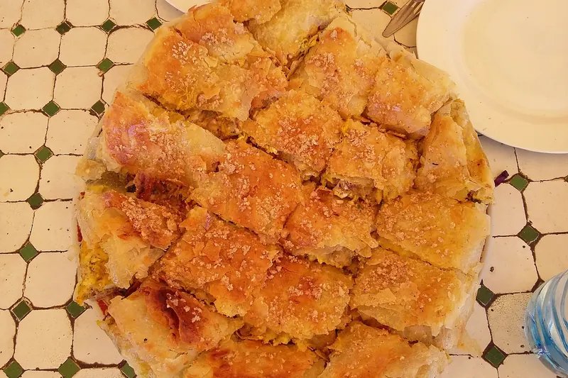 A round pastilla pie dusted with cinnamon and sugar