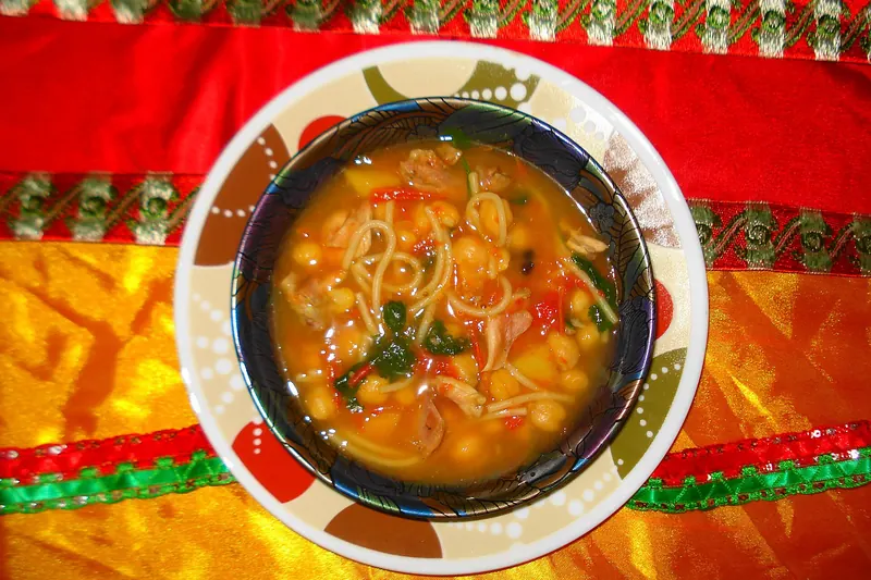 A bowl of harira soup with dates on the side