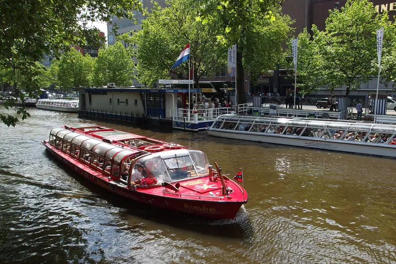 A canal tour boat passing beneath a bridge in Amsterdam