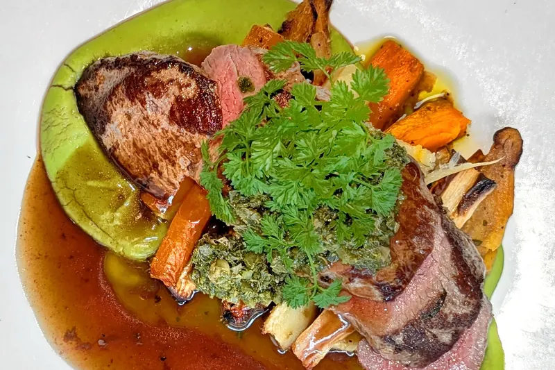 A plated lamb dish with roasted vegetables, a South Island specialty