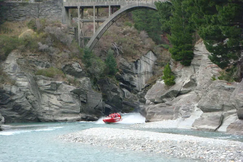 A jet boat speeding through the narrow Shotover River canyon