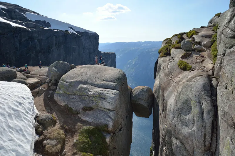A hiker standing on the Kjeragbolten boulder above Lysefjord