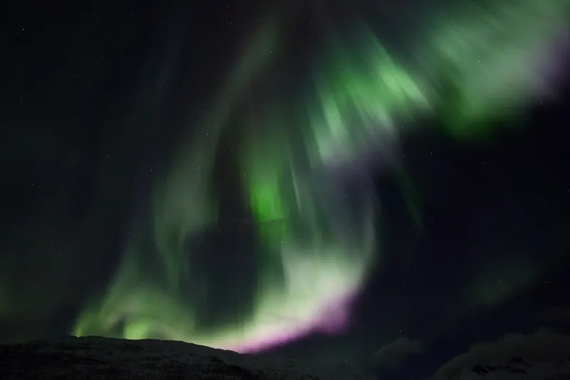 The aurora borealis glowing green over the Arctic landscape near Tromsø