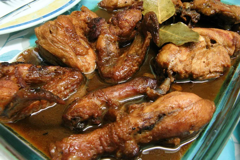 A plate of chicken adobo braised in soy and vinegar with rice