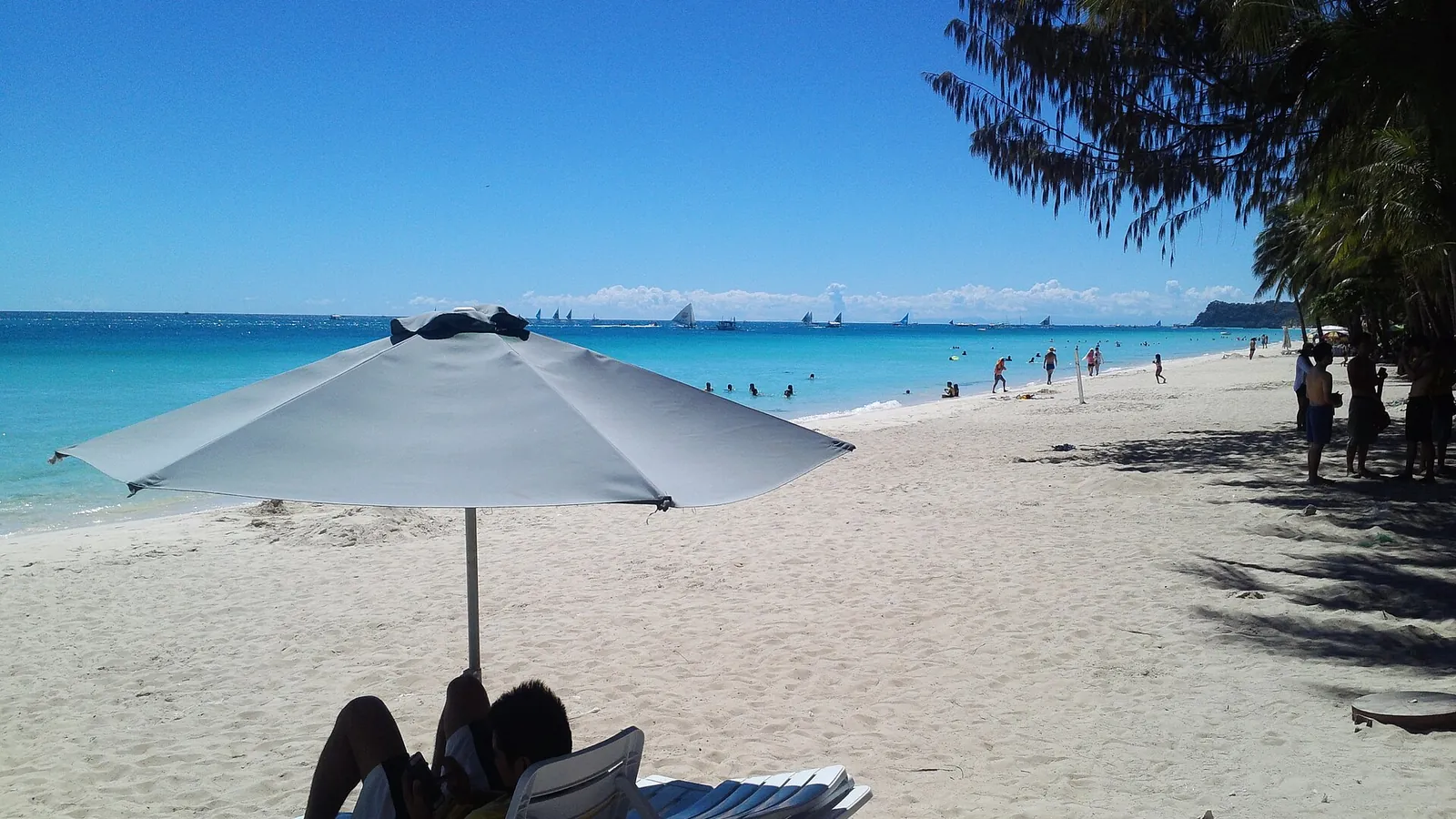 The wide white sand of White Beach on Boracay with palms and blue water
