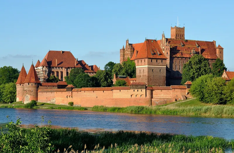 A wide panorama of Malbork Castle along the Nogat river
