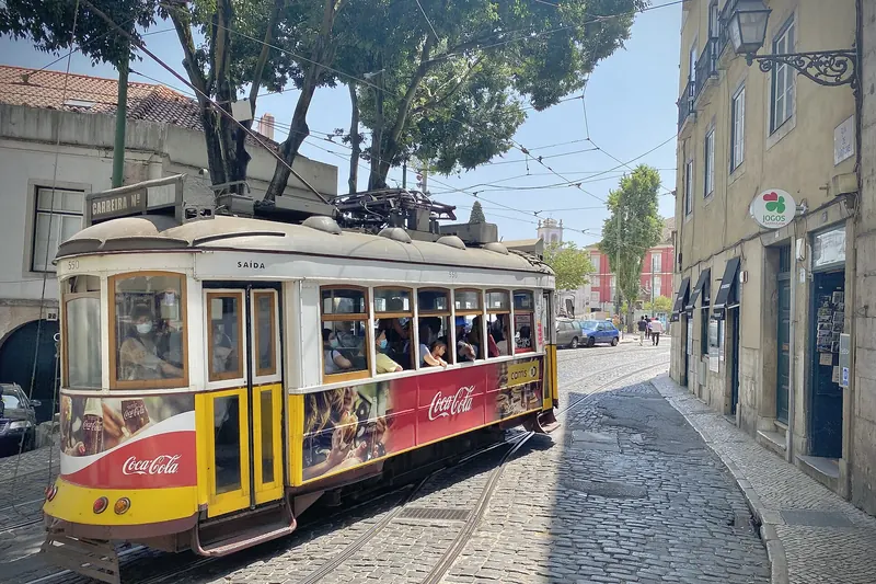 A traditional yellow tram climbing through Lisbon's Alfama district