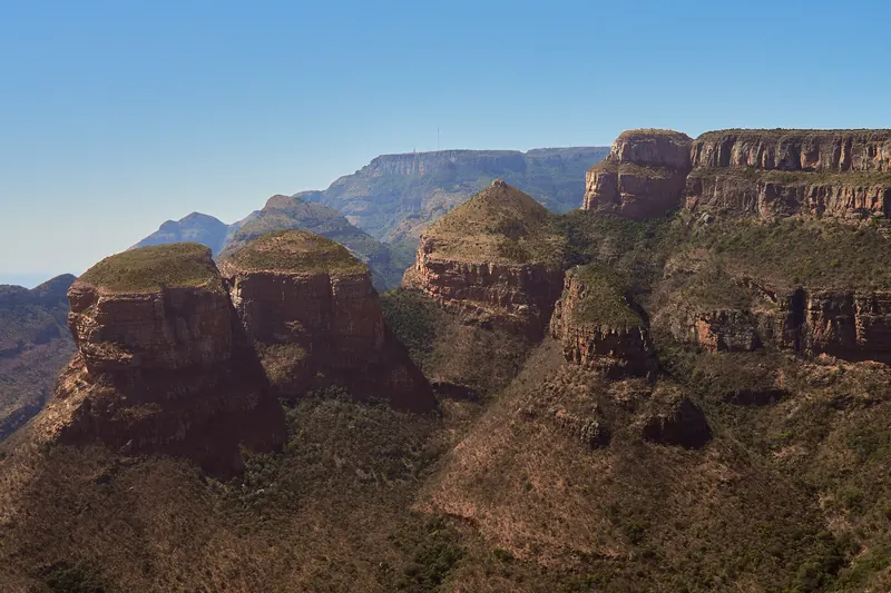 A wide panorama of the Blyde River Canyon with cliffs and a green valley
