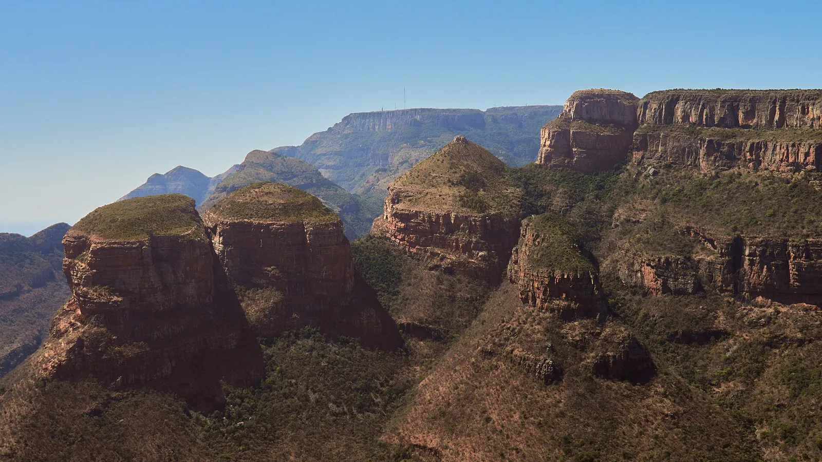 A wide panorama of the Blyde River Canyon with cliffs and a green valley