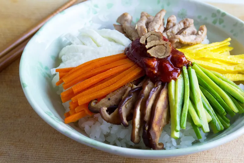 A bowl of bibimbap with rice, vegetables, egg and chilli paste