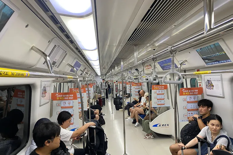 A busy Seoul subway train platform with waiting passengers