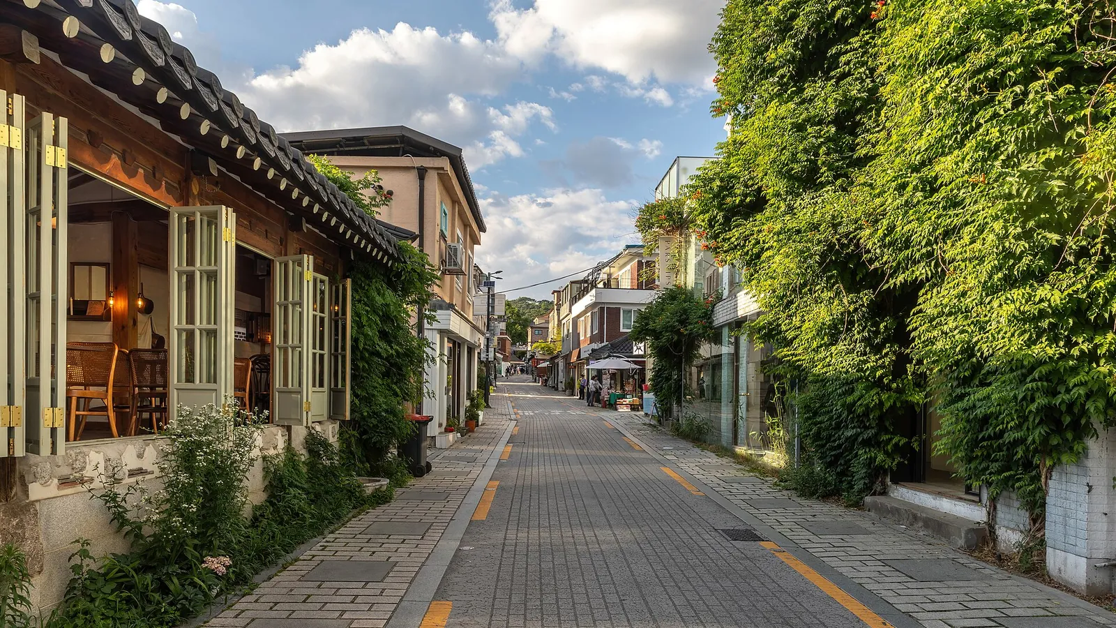 A quiet hanok-lined street in Seoul covered in climbing plants at golden hour