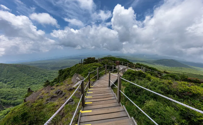 A wooden staircase along the Yeongsil Trail with Hallasan mountains beyond
