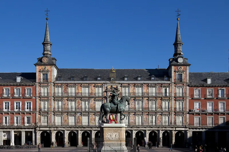 The arcaded Plaza Mayor in Madrid with its red-painted facade and clock tower