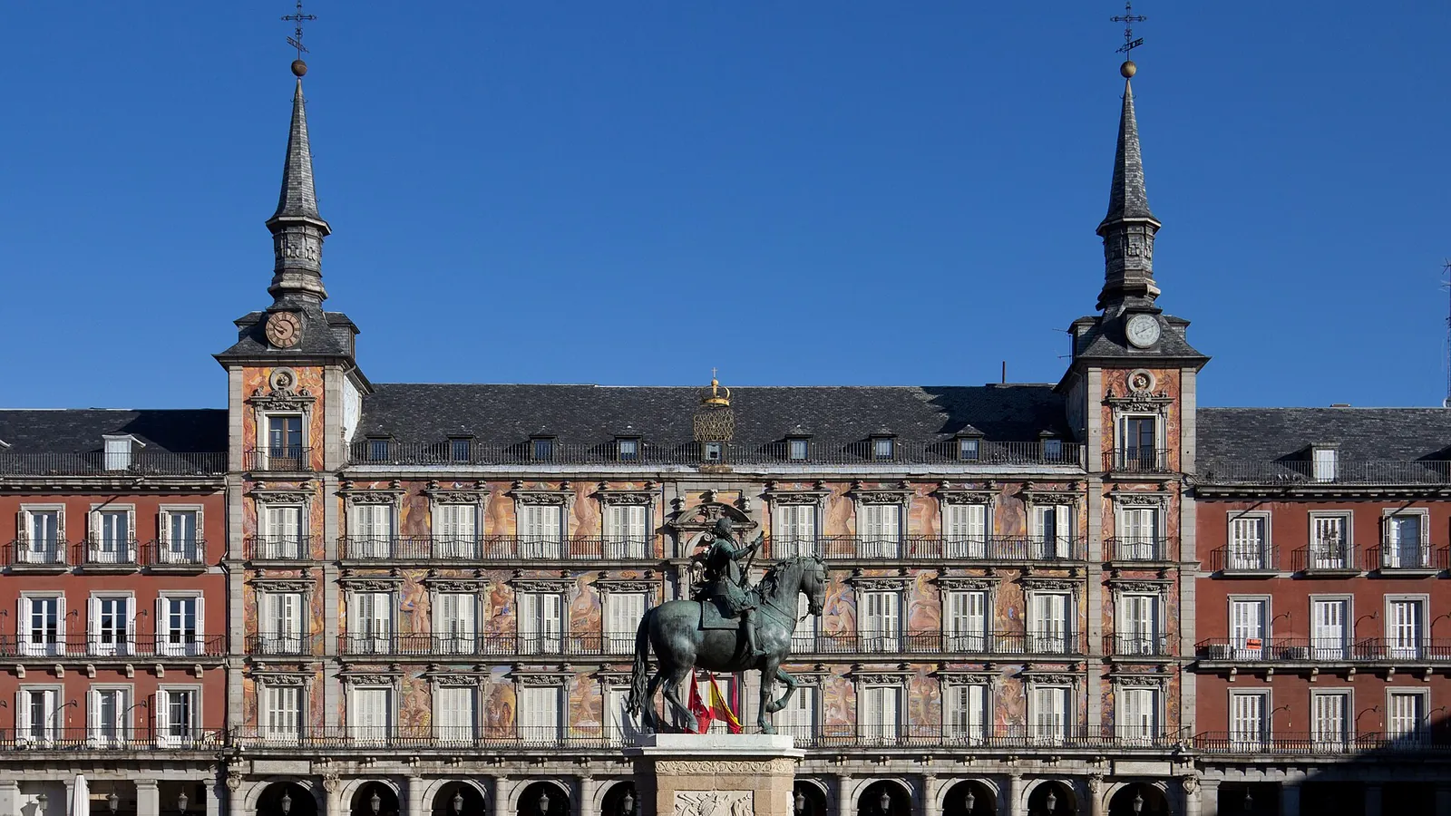 The arcaded Plaza Mayor in Madrid with its red-painted facade and clock tower
