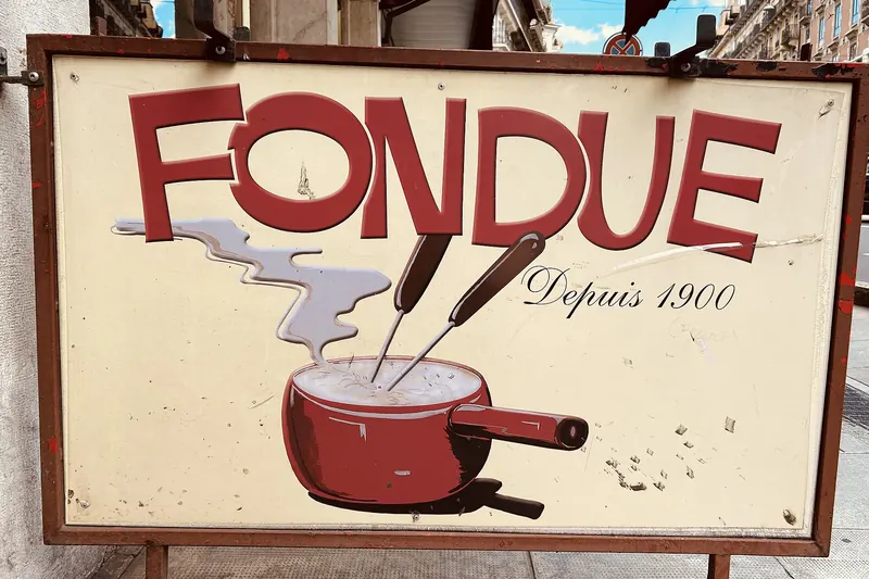 A pot of melted cheese fondue with bread cubes