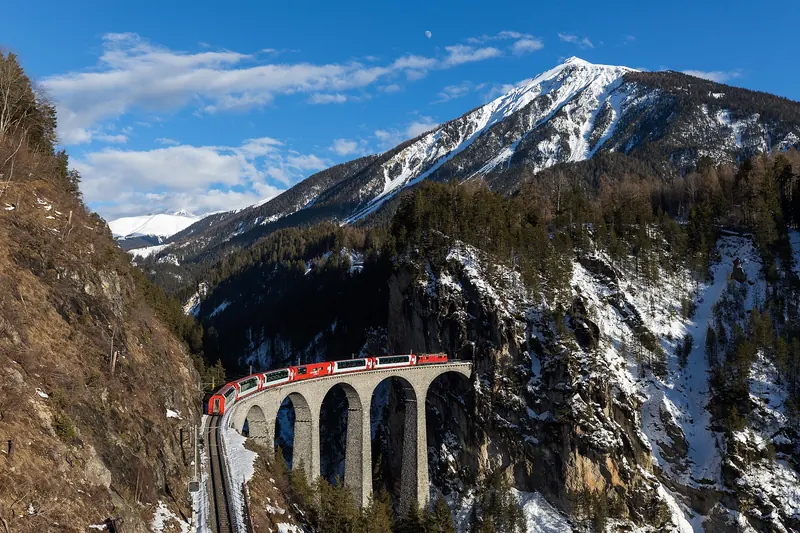 The red Glacier Express crossing the curved Landwasser Viaduct