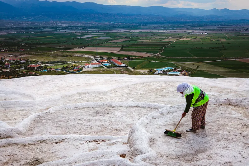 Visitors walking barefoot up the white travertine terraces