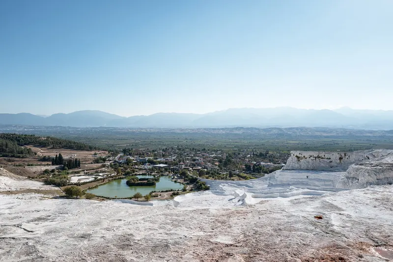 White stepped travertine terraces filled with pale blue water at Pamukkale