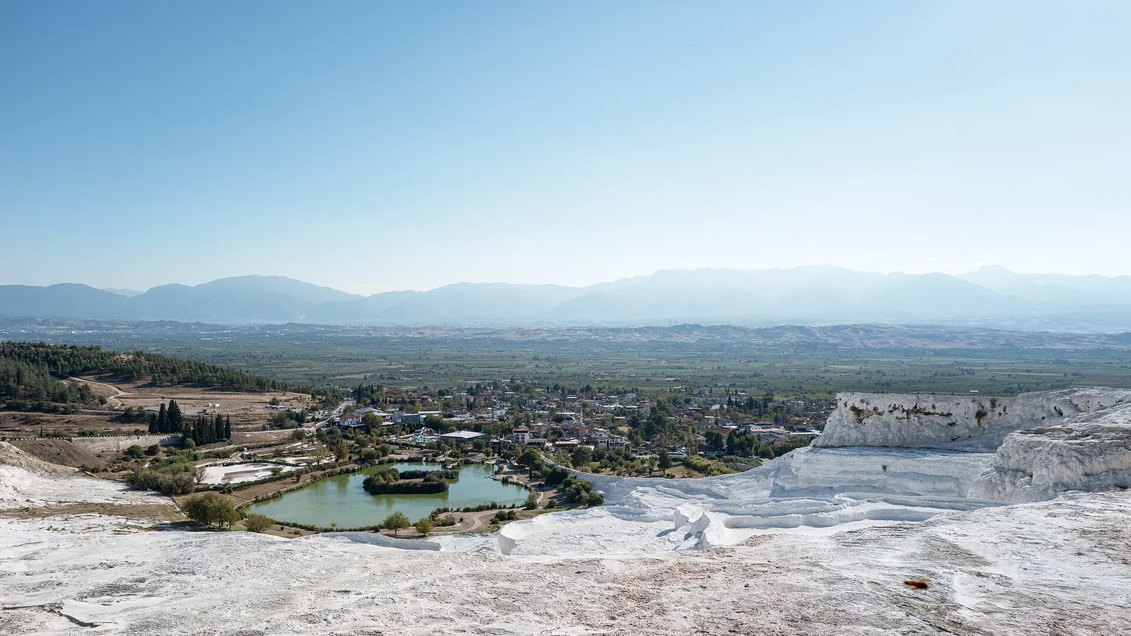 White stepped travertine terraces filled with pale blue water at Pamukkale