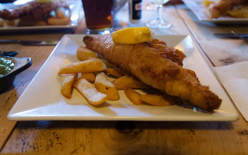 A plate of battered haddock and chips at an English pub