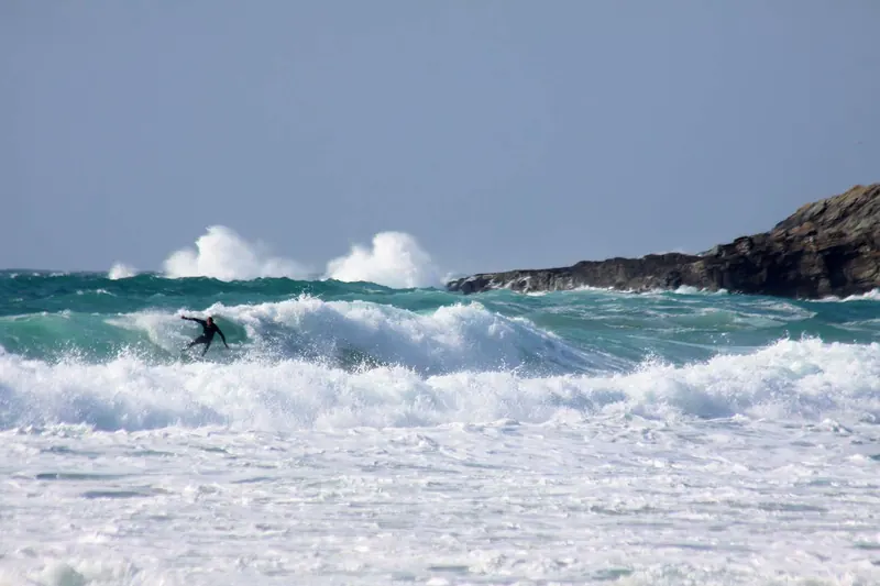 A surfer riding a wave at Fistral Beach