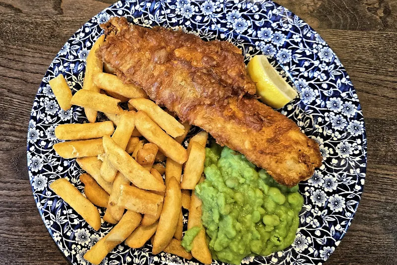 A plate of fish and chips with mushy peas