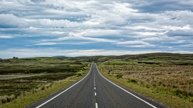 An empty single-carriageway road across open Highland moorland