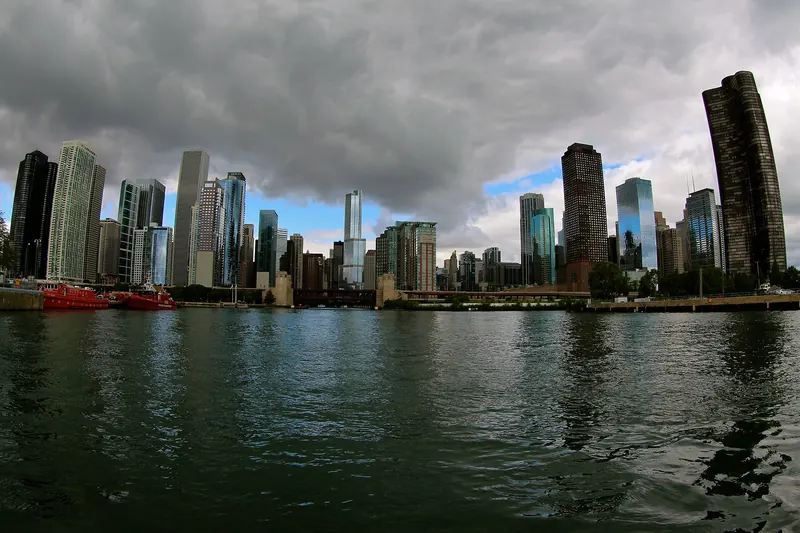 A tour boat on the Chicago River between the glass and stone towers of the downtown Loop