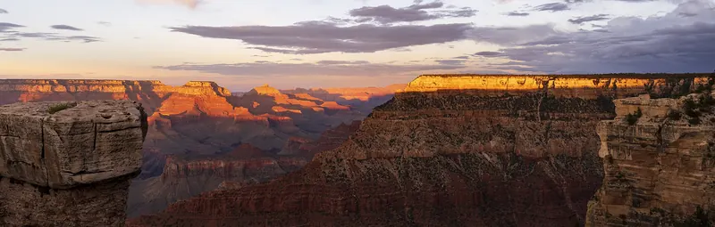 Layered red and orange buttes of the Grand Canyon receding into haze at sunset