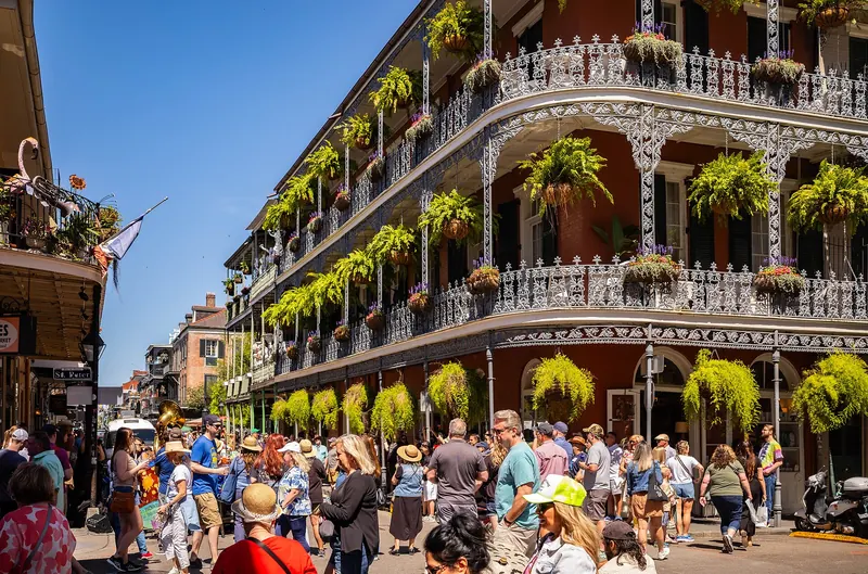 Cast-iron balconies hung with plants above a busy street in the French Quarter of New Orleans