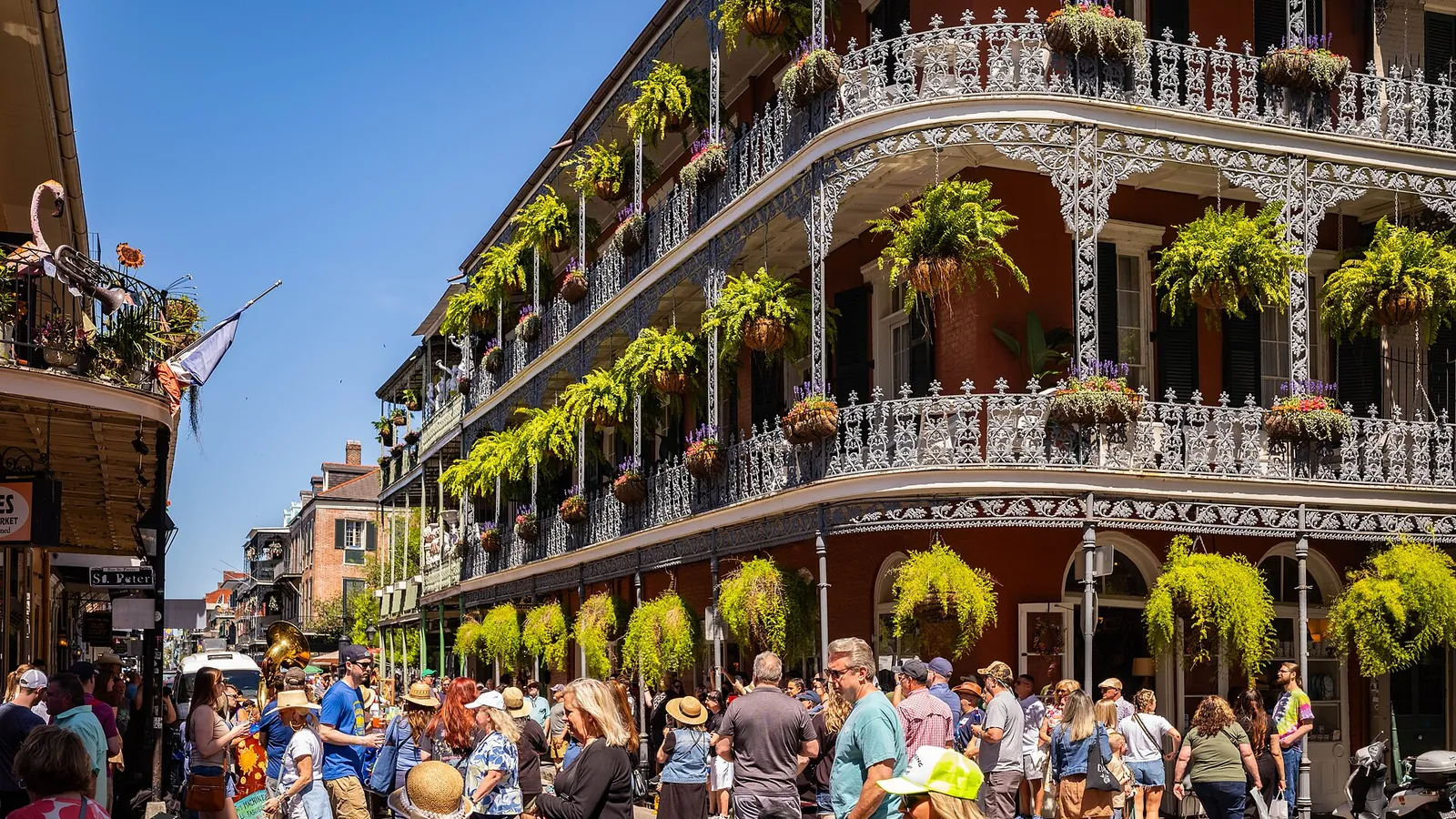 Cast-iron balconies hung with plants above a busy street in the French Quarter of New Orleans