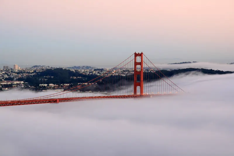 The Golden Gate Bridge in orange light with the Pacific behind it at sunset