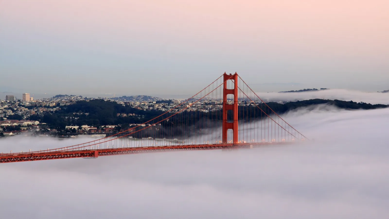 The Golden Gate Bridge in orange light with the Pacific behind it at sunset