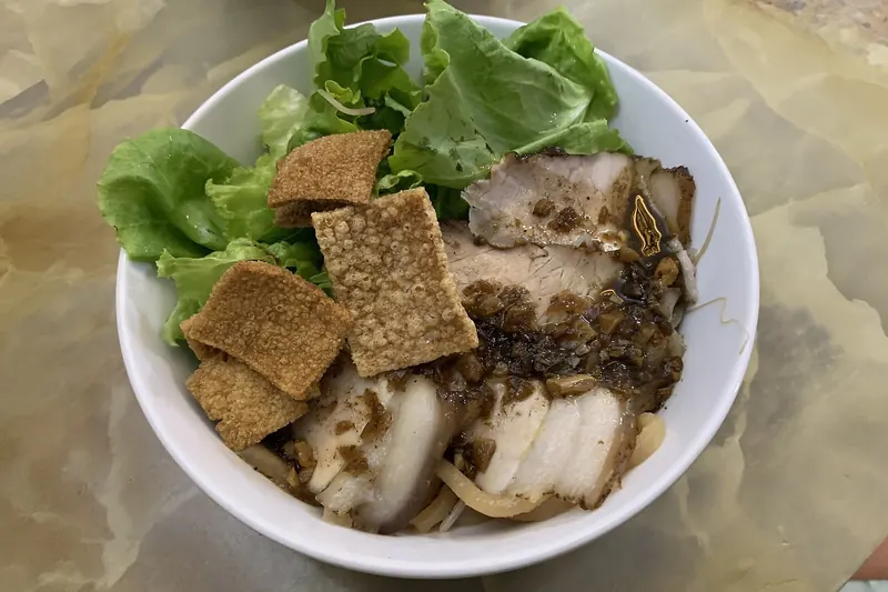 A bowl of cao lau noodles with pork and herbs in Hoi An