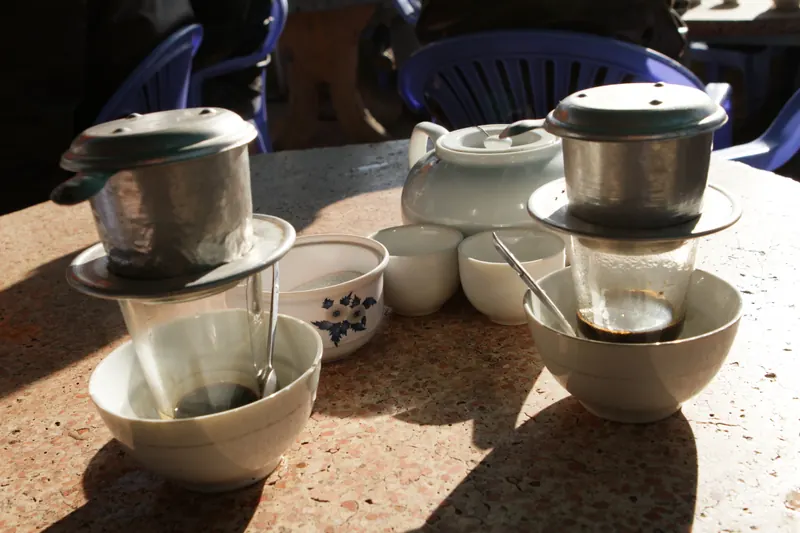 Vietnamese coffee dripping through a small metal filter into a glass