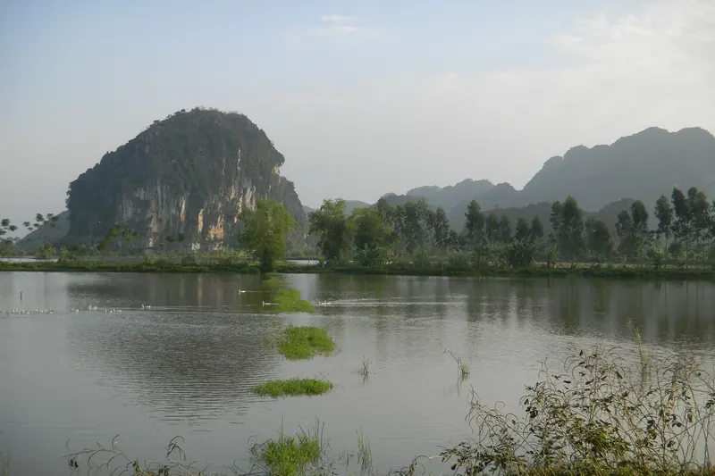 A rowing boat on the river at Tam Coc among limestone hills and rice fields